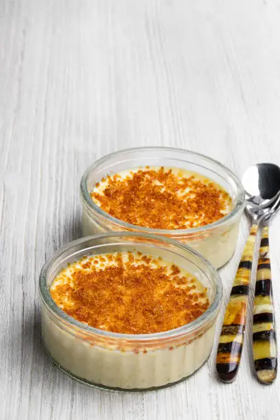 Closeup  of creme brulee in glass jars on white wooden table