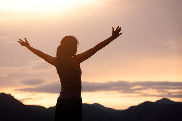 silhouette girl standing on mountain and rise up her hand stock photo