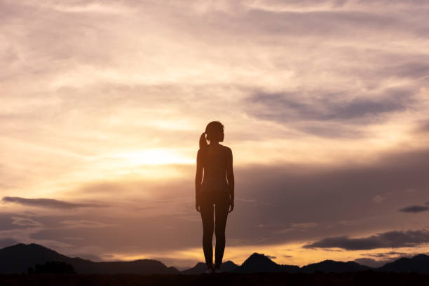silhouette lonely girl standing on top of mountain stock photo