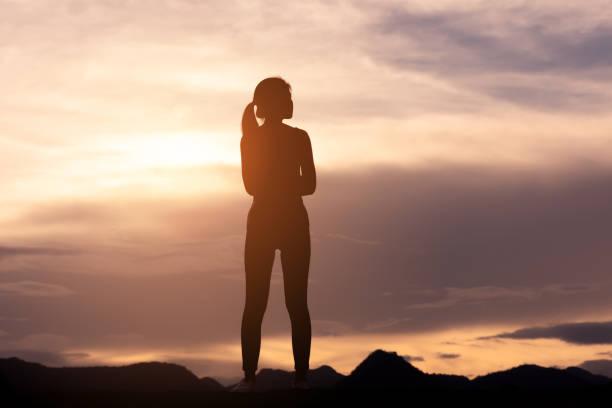 silhouette lonely girl standing on top of mountain stock photo
