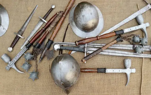 Photo of Medieval weapons and helmets on jute canvas.