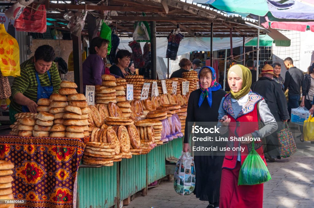 Non bread display at the street market Bishkek, Kyrgyzstan - September 25, 2018: Rows of food stalls at Osh Bazaar, selling traditional central asian round, flat bread Non or Naan and local people walking along with goods in hand Kyrgyzstan Stock Photo