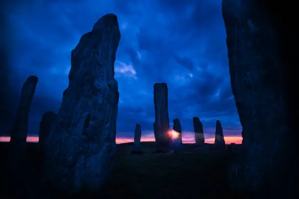 Callanish Standing Stones, dating from 5,000 years ago, look spooky and mysterious at night against a dramatic sliver of pink in the dark sky, Isle of Lewis, Outer Hebrides, Scotland, UK, Europe