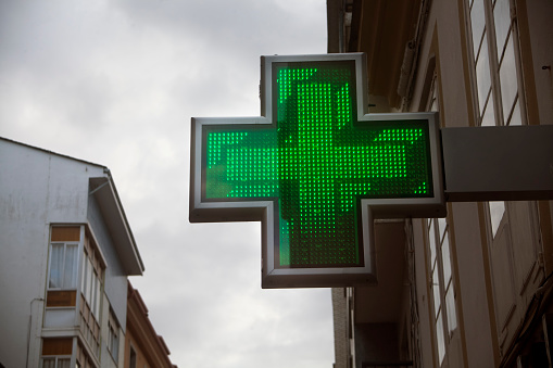 Símbolo de farmacia en la calle, edificios altos, cruz verde. photo
