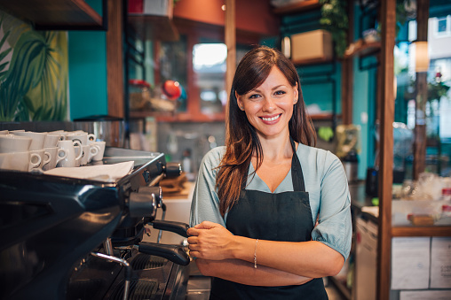 Portrait of a beautiful waitress wearing an apron, smiling at camera.