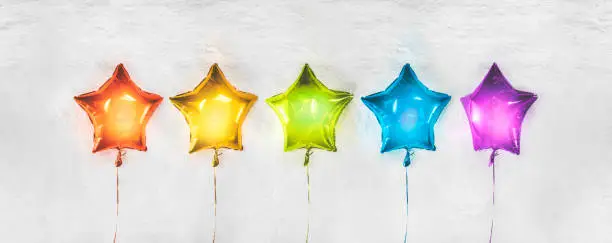 Photo of Review Concept with rainbow star balloons on a white stone background