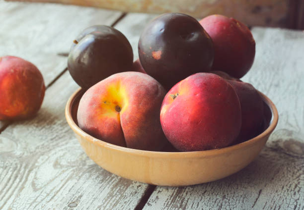 istock Ripe peaches and plums in a plate on a rustic background 1168616197