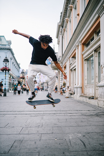 Vintage toned street style fashion portrait of a  young man doing skateboard tricks on the streets of downtown Belgrade, Serbia, Southeastern Europe.