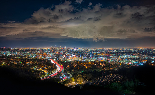 A slow shutter speed photograph of downtown Los Angeles, California, USA after a sunset on a cloudy night,  from Mulholland Drive.