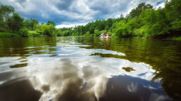 riflesso delle nuvole nel bellissimo fiume e persone in catamarano - spring forest scenics reflection foto e immagini stock