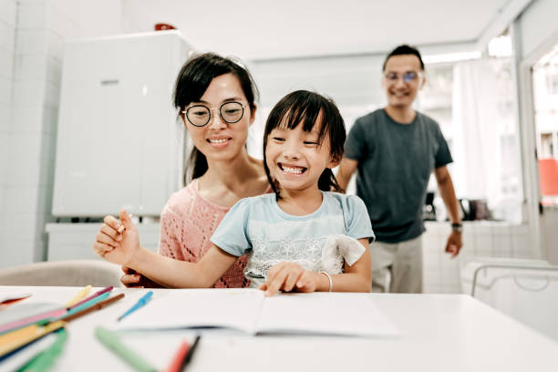 istock Mother and daughter drawing together, father doing laundry behind them 1168618797