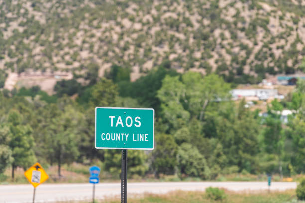 village de trampas dans la rue historique de ville de high road à taos dans les montagnes avec le signe pour la ligne de comté de taos dans le désert - new mexico sign santa fe new mexico road trip photos et images de collection