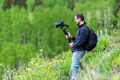 Snodgrass trail with man filming holding camera stabilizer gimbal in Mount Crested Butte, Colorado in summer
