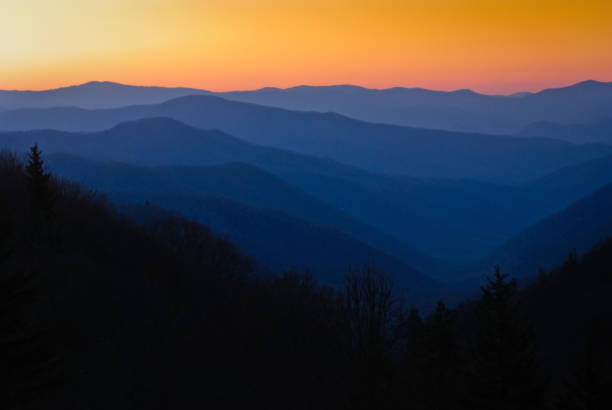 istock Mountain ranges appear blue against an orange sky at sunrise. 1168619125