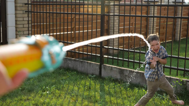 istock cute schoolboy enjoys drops flowing from water gun jet 1168620429