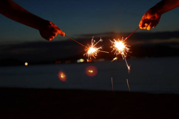 istock People enjoying hand-held fireworks on the beach 1168621063