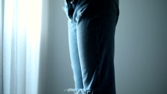 Young Woman Trying On Her New Jeans In Bedroom