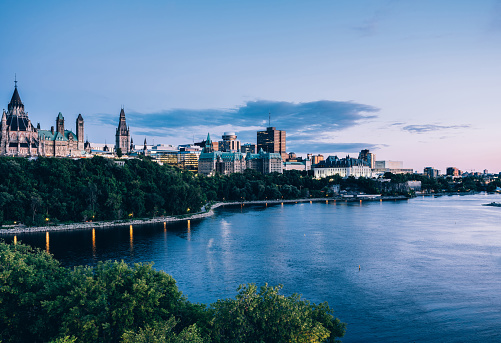Dusk time Urban landscape of Canadian Parliament building in downtown Ottawa, capital city of Canada. View overlooking Ottawa river, dividing the city on two Provinces (Ontario and Quebec).