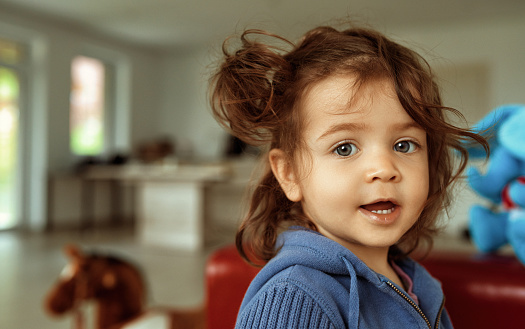 Little girl with messy hair standing in the living room