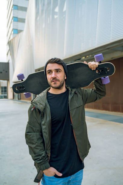istock Cool man at the street carrying his longboard 1168631202