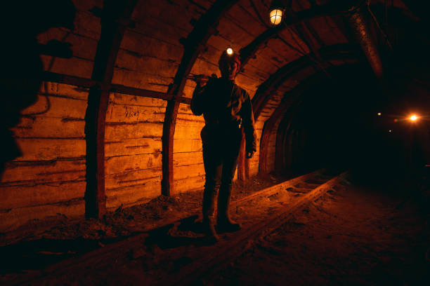 istock A man in work overalls and a helmet with a jackhammer on his shoulder is standing on the rails. Silhouette in red. Mine worker 1168633062