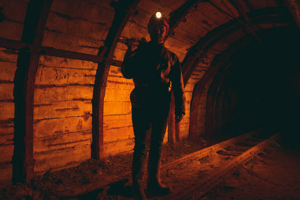 istock A man in work overalls and a helmet with a jackhammer on his shoulder is standing on the rails. Silhouette in red. Mine worker 1168633155