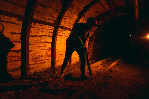istock A man in work overalls and a helmet with a jackhammer on his shoulder is standing on the rails. Silhouette in red. Mine worker 1168633689