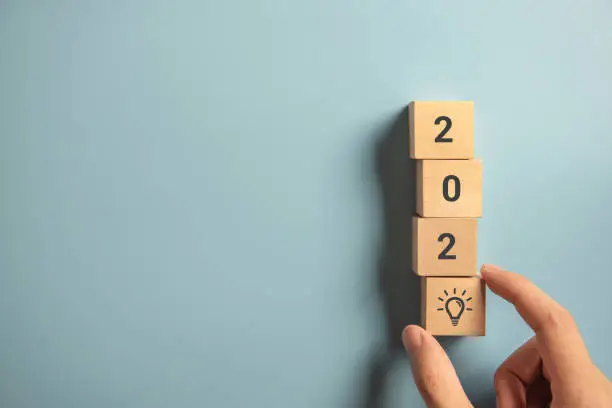 Photo of Creativity inspiration concepts, Woman hand arranging wood block with new year 2020 and lightbulb icon, planning ideas.