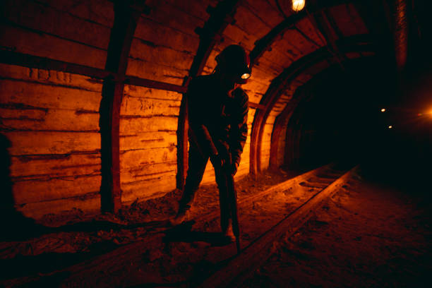 istock A man in work overalls and a helmet with a jackhammer on his shoulder is standing on the rails. Silhouette in red. Mine worker 1168637246