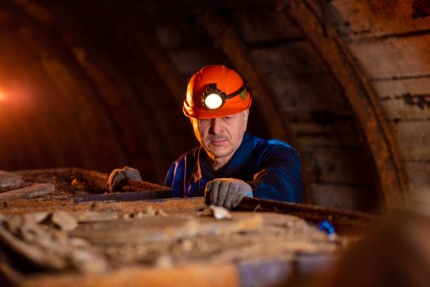 istock An elderly man dressed in work overalls and a hard hat is standing near the old caravan. Mine worker 1168637298