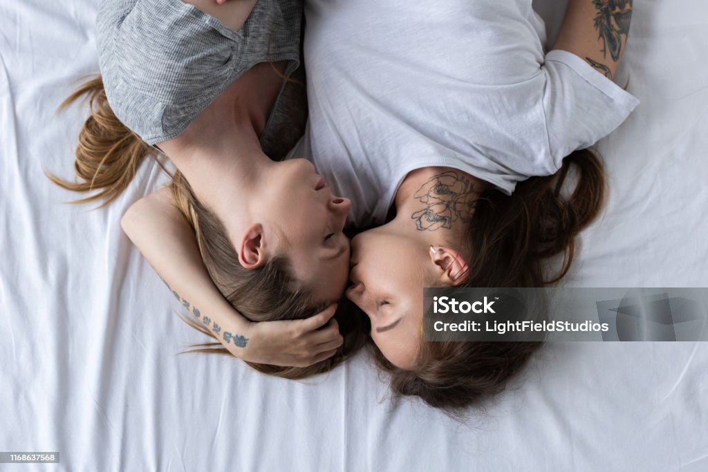 top view of two lesbians embracing and kissing on bed Gay Couple Stock Photo