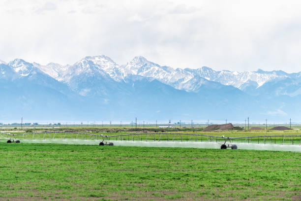 route 285 w kolorado z zieloną farmą w pobliżu saguache i widokiem na góry skaliste z opryskiwaczem wodnym - sprinkler park summer spray zdjęcia i obrazy z banku zdjęć