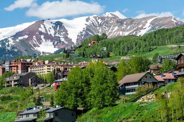 Photo of Mount Crested Butte snow marooon color mountain in summer with green lush color on hills and houses cityscape