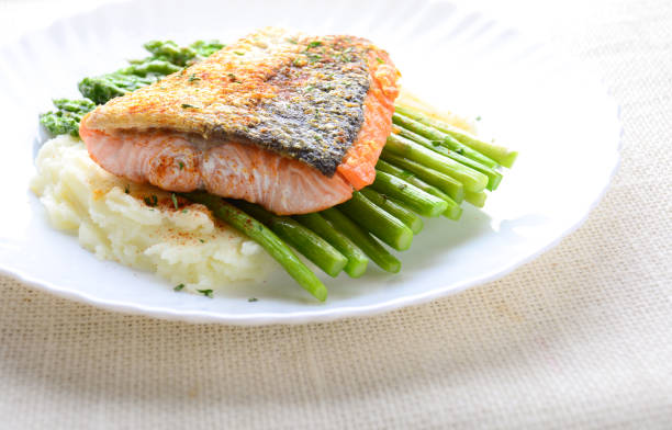 istock Grilled salmon garnished with asparagus and herbs and mashed potatoes, served on white plated.
