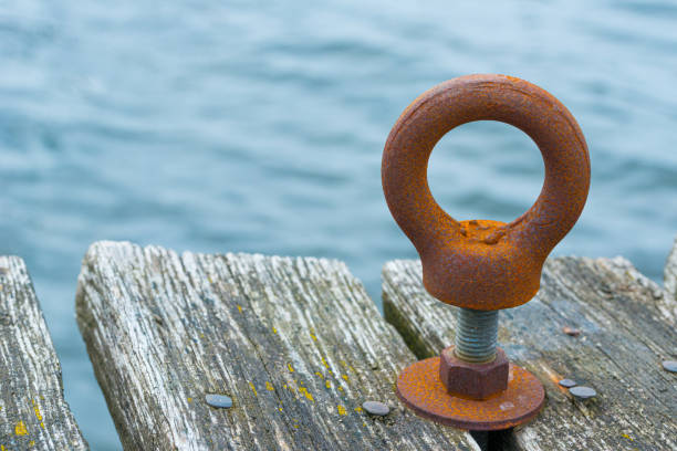 A rusty metal ring on a bolt mounted on a wooden pier.