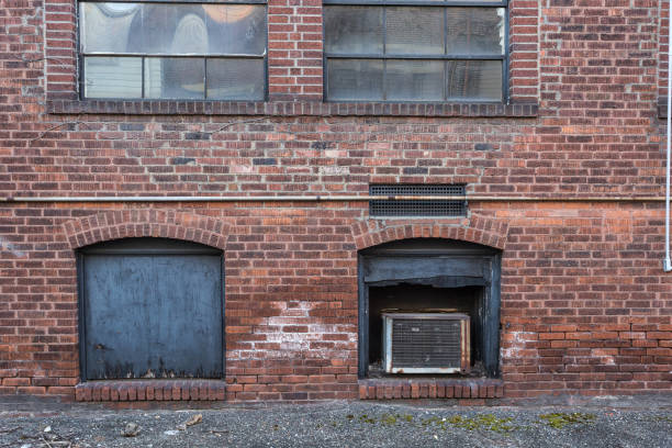istock Back of red brick building with covered windows in alley 1168647529