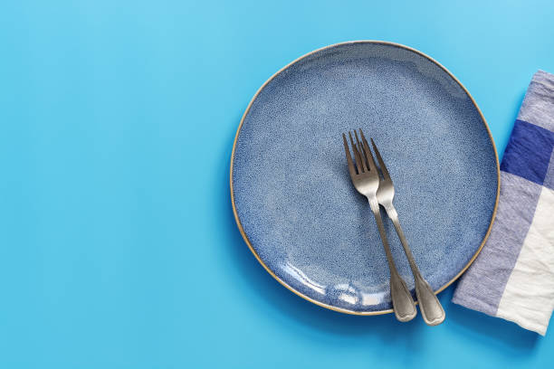 istock Flat lay empty plate, forks and napkin on a blue background. Top view, copy space. 1168649458