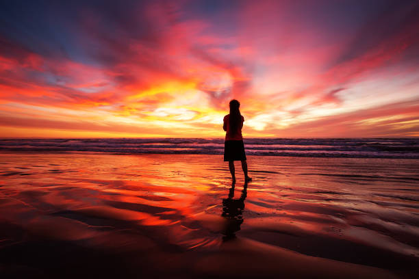 istock woman walking alone on the beach in the sunset 1168649486