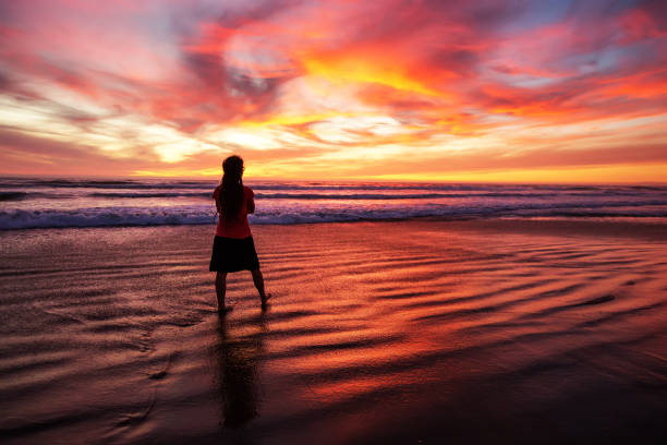 istock woman walking alone on the beach in the sunset 1168649494