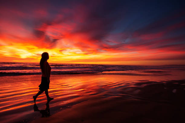 istock woman walking alone on the beach in the sunset 1168649508