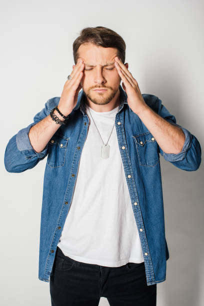 istock young man in stylish clothes with closed eyes and headache holding head 1168651697