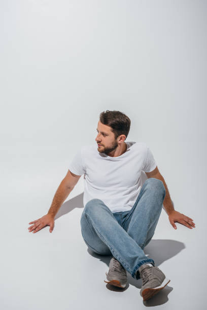 istock handsome man sitting on floor and looking away 1168651698