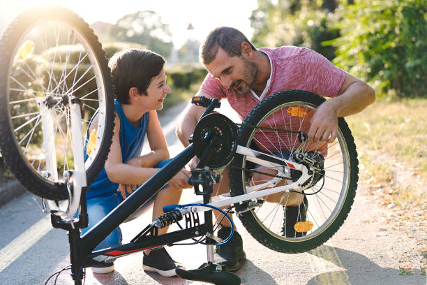 Father and son repairing a bicycle in city. Family cycling stock photo