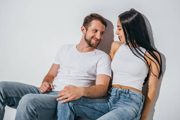 istock two young people in love sitting on floor and looking at each other 1168651742