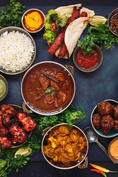 various indian dishes featuring  rogan josh, chicken tikka masala,tandoori chicken wings  and  kebabs, with rice and naan bread - cooked vertical high angle view lentil imagens e fotografias de stock