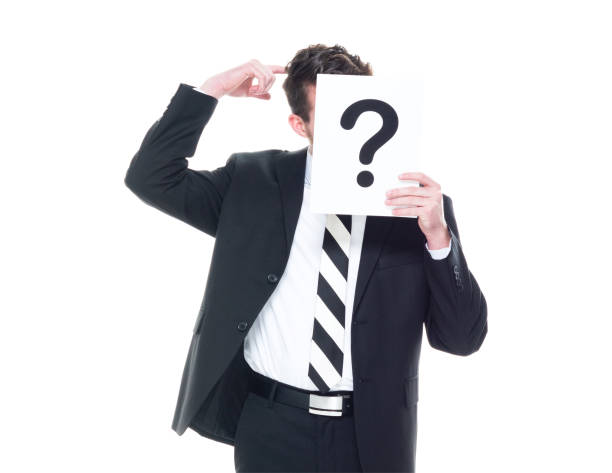 istock Handsome businessman wearing a black suit - is hiding behind a question mark sign 1168660103