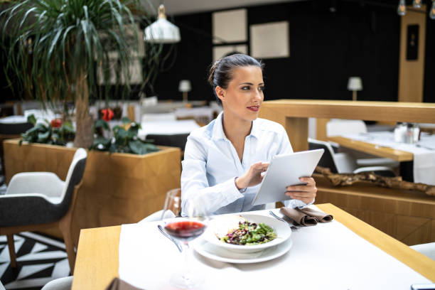 istock Smiling businesswoman sitting in restaurant and using tablet 1168662462