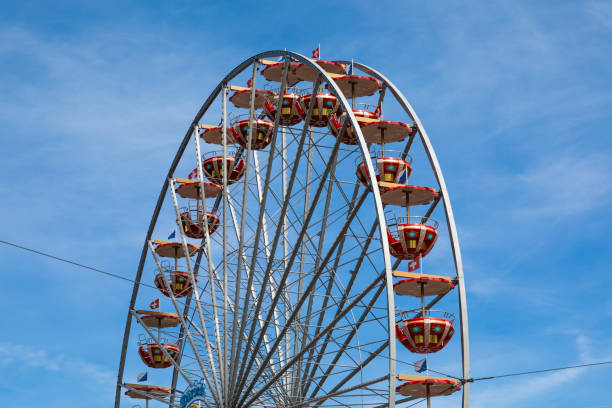 istock Red Ferris wheel in front of blue sky with cloudy sky 1168669780