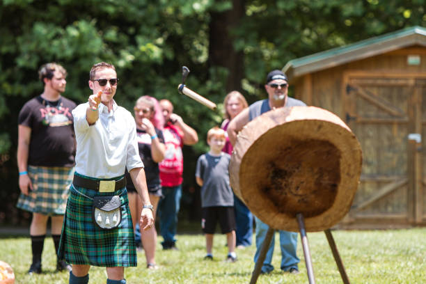 Man Throws Hatchet in Axe Throwing Exhibition At Highland Games Blairsville, GA, USA - June 9, 2018:  A man throws a hatchet at a wood target in an axe throwing exhibiton  at the Blairsville Scottish Highland Games at Meeks Park on June 9, 2018 in Blairsville, GA. axe throwing stock pictures, royalty-free photos & images