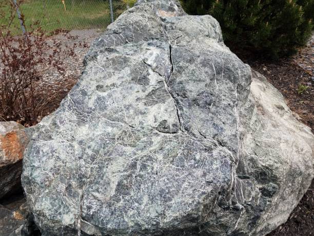 large white stone or rock or boulder with veins and metal fence